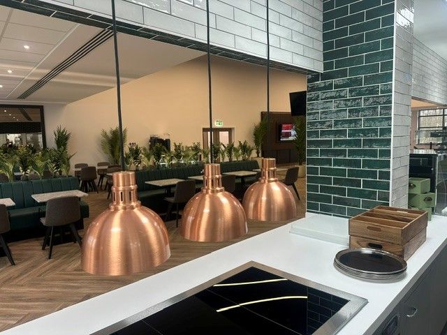 Copper heat lamps over the servery pass, looking out to the restaurant